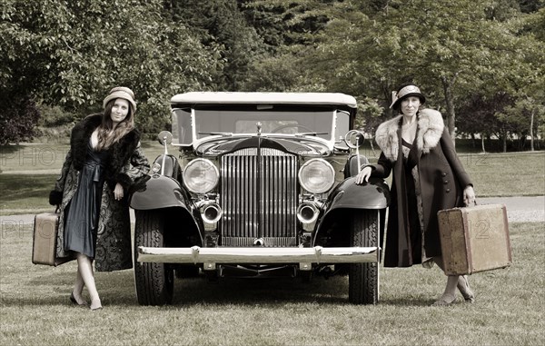 Caucasian women with luggage by vintage car