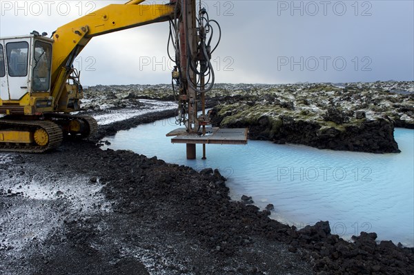 Machinery drilling into lake in arctic landscape