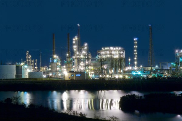 Factory near lake illuminated at night