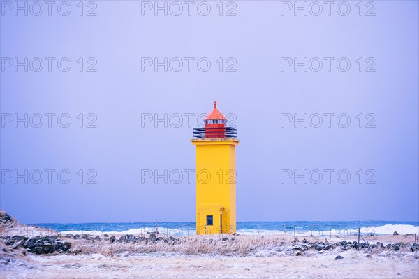 Yellow lighthouse on snowy coastline