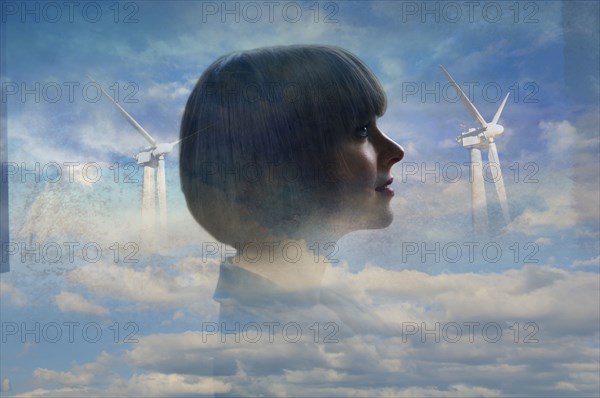 Double exposure of businesswoman and wind turbines in clouds