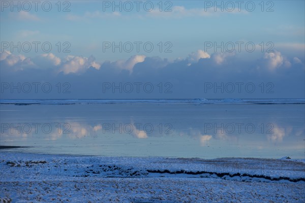 Clouds reflected in still ocean in arctic landscape