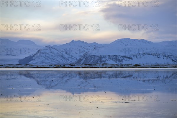 Mountains reflected in still ocean in arctic landscape