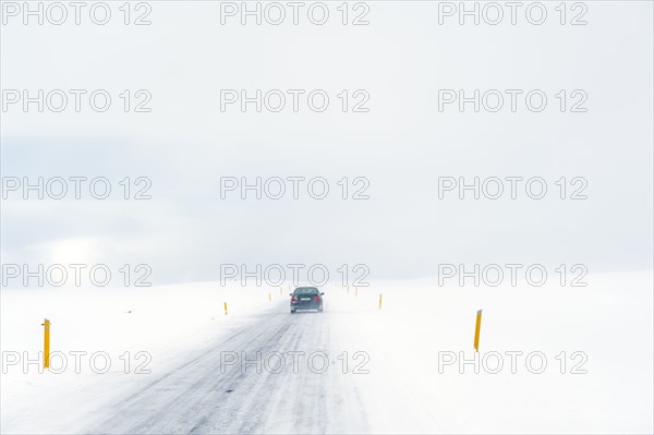 Car driving on rural road in snowy landscape