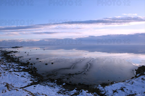 Clouds reflected in still ocean in arctic landscape