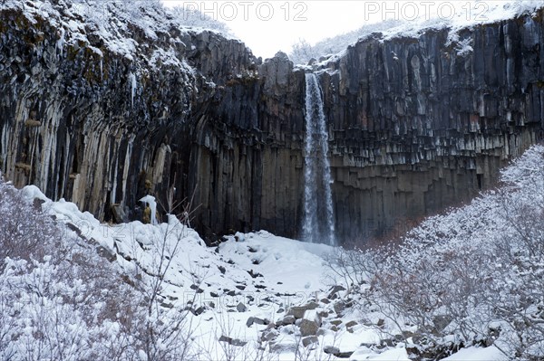 Waterfall and steep cliff in snowy landscape