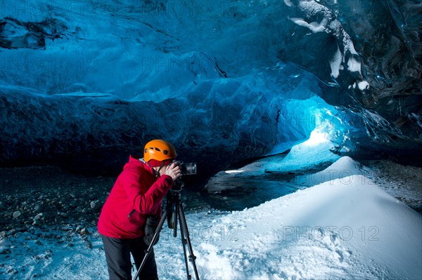 Photographer taking photograph in ice cave