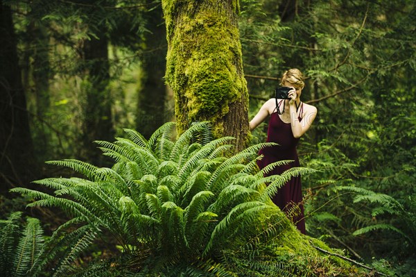 Caucasian woman taking photograph in forest