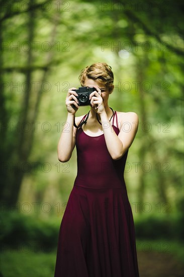 Caucasian woman taking photograph in forest