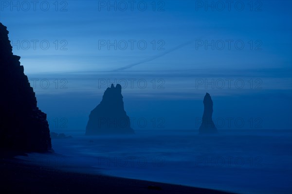 Rock formations in ocean at misty beach