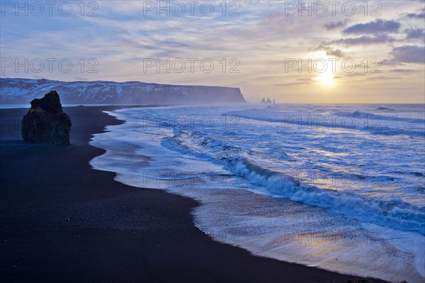 Waves washing up by rock formation on beach