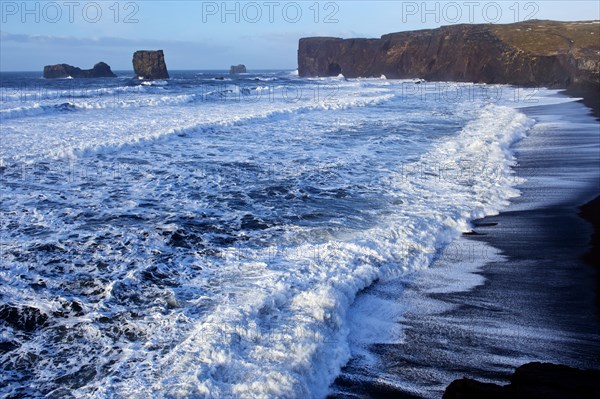 Waves washing up by rocky cliffs on beach