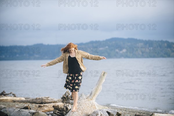 Girl balancing on driftwood on beach