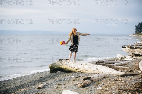 Girl balancing on driftwood on beach