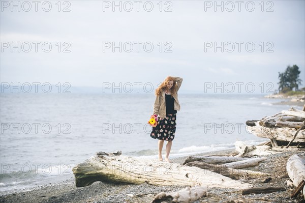 Girl standing on driftwood on beach