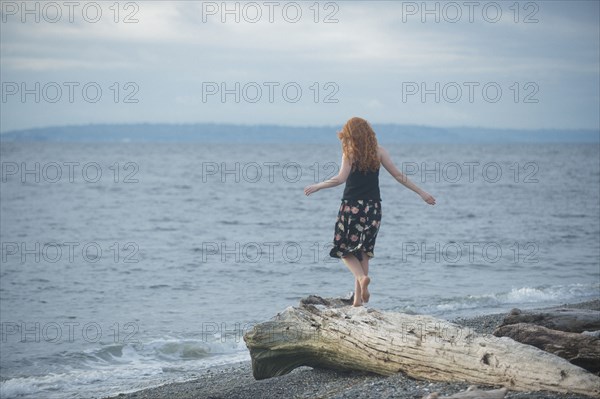 Girl walking on driftwood on beach