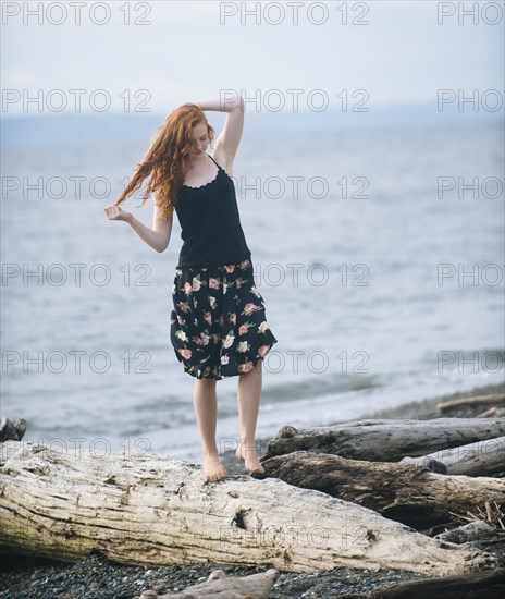 Girl walking on driftwood on beach