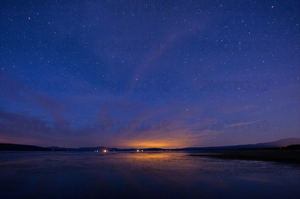 Still rural lake under starry night sky