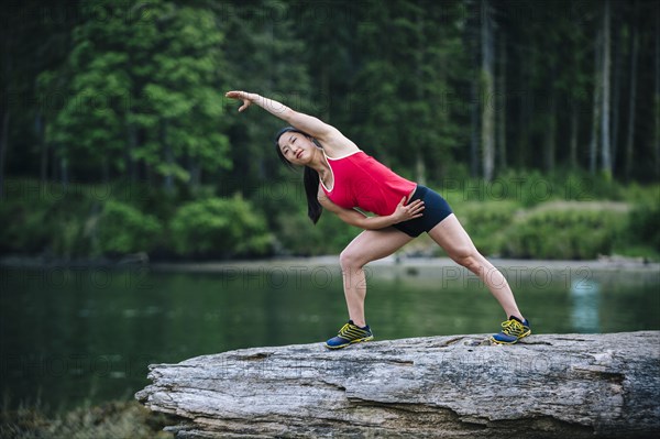 Korean runner stretching on rock near lake