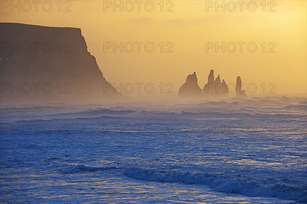 Silhouette of rock formations in misty ocean