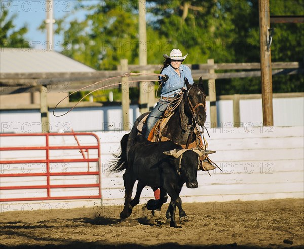 Caucasian cowgirl on horse throwing lasso in rodeo on ranch