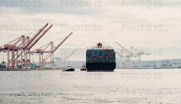 Tugboat and container ship in industrial harbor