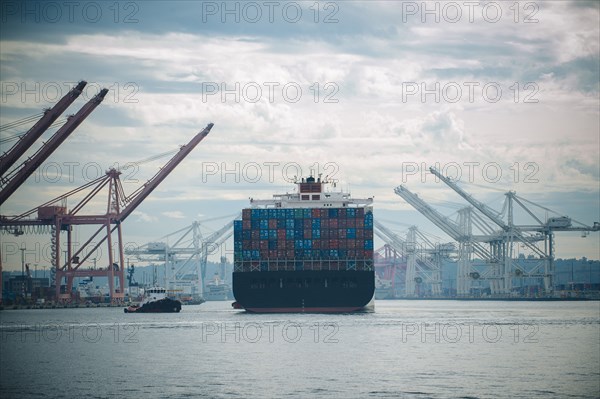 Tugboat and container ship in industrial harbor