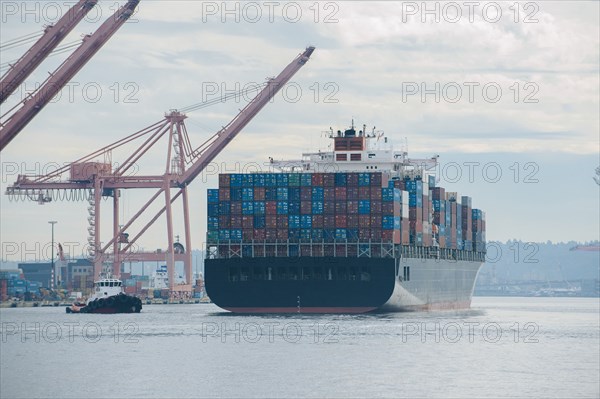 Tugboat and container ship in industrial harbor