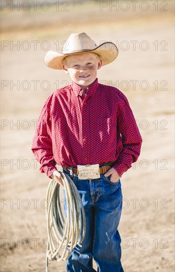 Caucasian boy in cowboy outfit carrying lasso