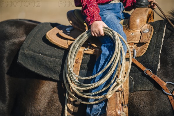 Caucasian boy carrying lasso and riding horse