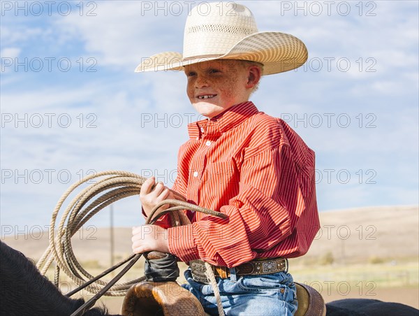 Caucasian boy on horse carrying lasso