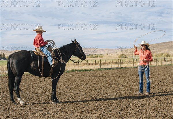 Caucasian woman teaching boy to use lasso on ranch