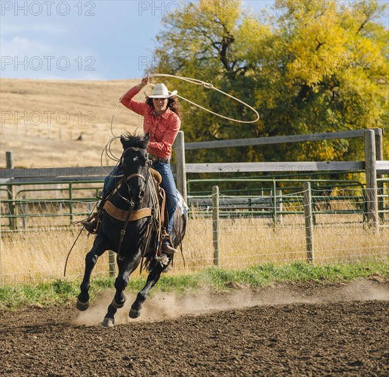 Caucasian woman using lasso on horse at rodeo