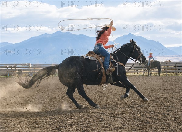 Caucasian woman using lasso on horse at rodeo
