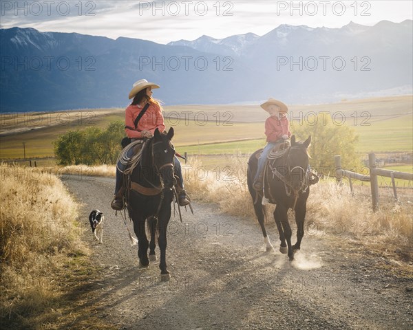 Caucasian mother and son riding horses on ranch