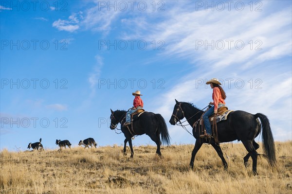 Caucasian mother and son on horseback on grassy hill