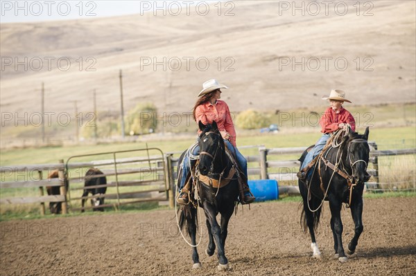 Caucasian mother and son riding horses on ranch