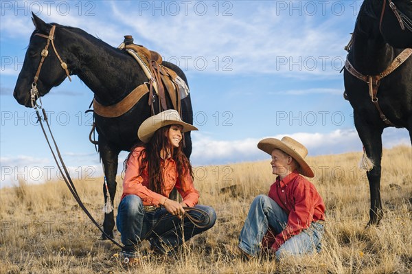 Caucasian mother and son with horses in grassy field