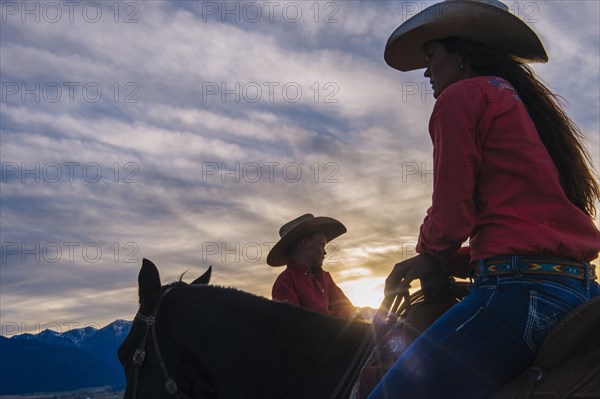 Caucasian mother and son riding horses at sunset