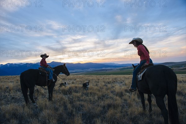 Caucasian mother and son riding horses in remote field