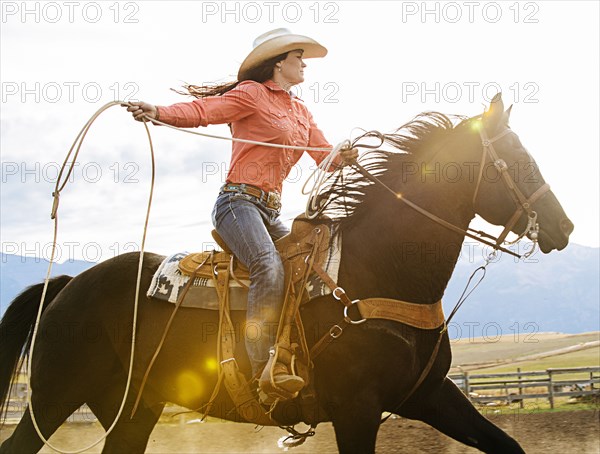 Caucasian woman on horse throwing lasso at rodeo