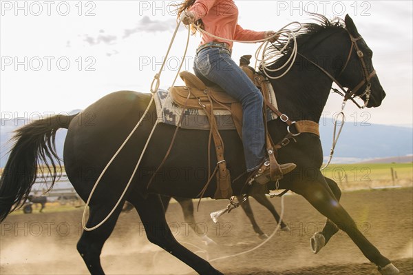 Caucasian woman on horse throwing lasso at rodeo