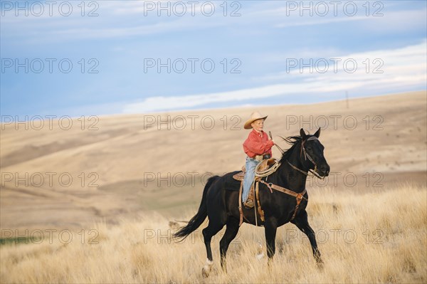 Caucasian boy riding horse in grassy field