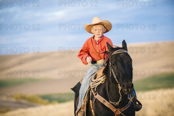 Caucasian boy riding horse in grassy field