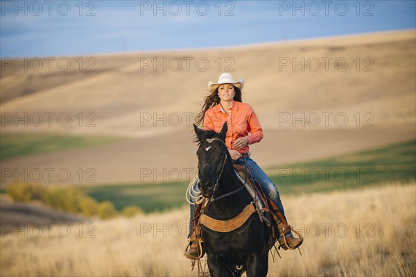 Caucasian woman riding horse in grassy field