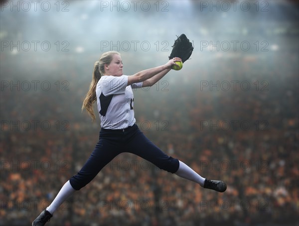 Caucasian softball player pitching ball in stadium