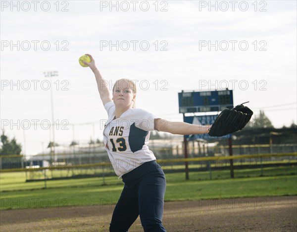 Caucasian softball player pitching ball in field