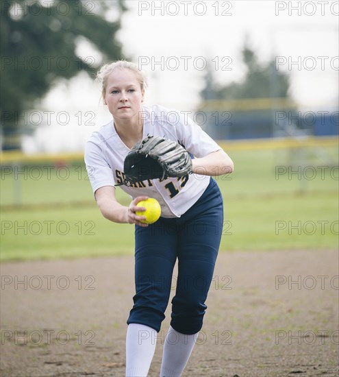 Caucasian softball player pitching ball in field