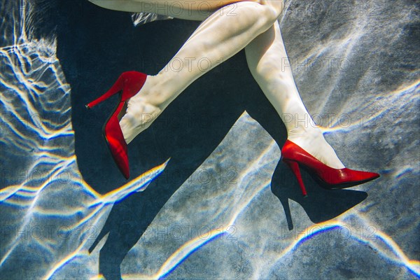 Legs of woman wearing high heels in swimming pool