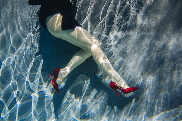 Legs of woman wearing high heels in swimming pool